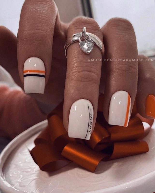 Бело-оранжевый маникюр с полосками и надписями на квадратных ногтях