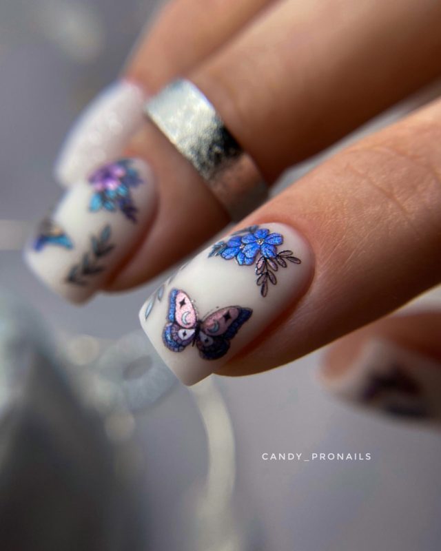 Молочный маникюр с голубыми бабочками, цветами и веточками на короткие ногти