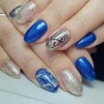 Блестящий маникюр в синем и бежевом цвете с узорами на овальных ногтях