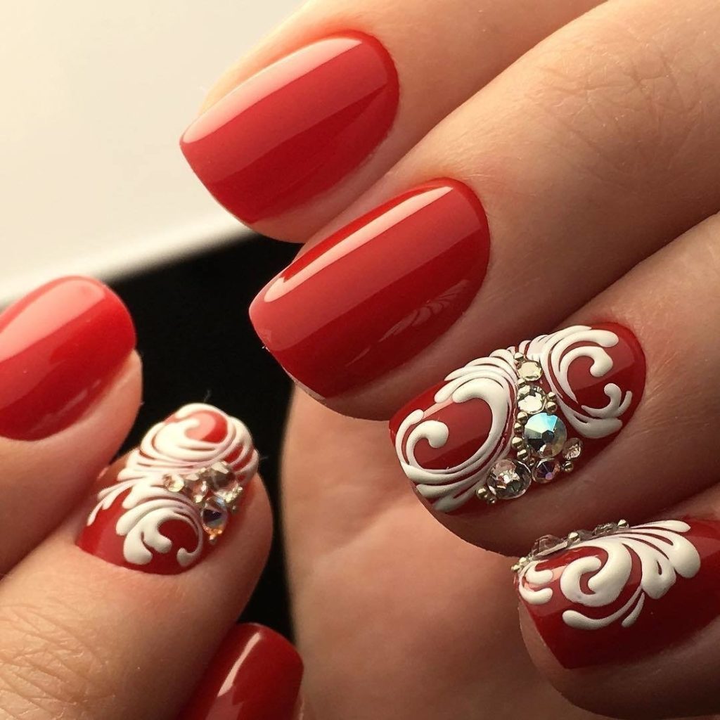 Красный яркий дизайн ногтей с глянцевым покрытием и белоснежными узорами на коротких ногтях