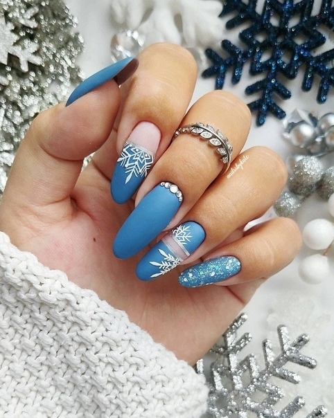 Матовый маникюр голубого цвета со снежинками на длинных овальных ногтях