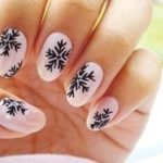 Нежный пудровый зимний дизайн ногтей с черным рисунком снежинок на овальных ногтях средней длинны