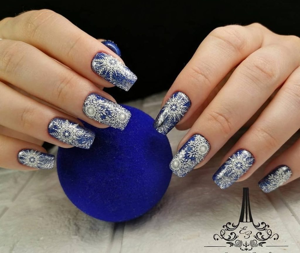 Новогодний синий маникюр с блестящими снежинками на ногти средней длины формы мягкий квадрат