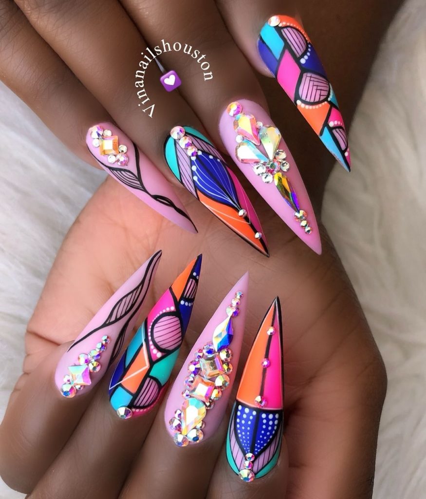 Контрастные яркие ногти-стилеты с геометрическим рисунком и декоративными кристаллами разной формы