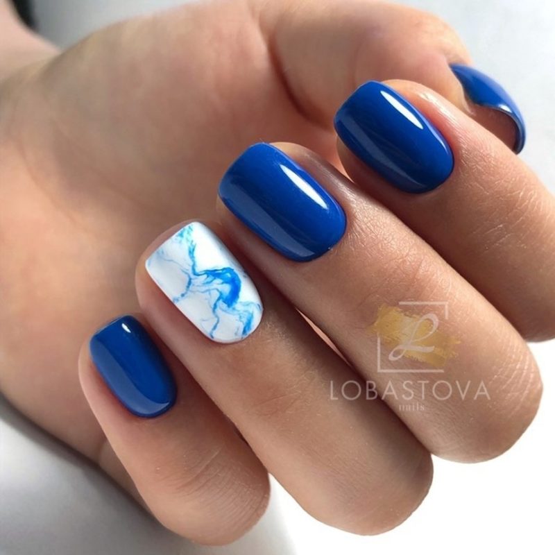 Насыщенный синий глянцевый маникюр с бело-голубым мраморным узором на безымянном ногте