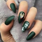 Оформление ногтей в темно-зеленом цвете с белыми снежинками и оленем из декоративных камней