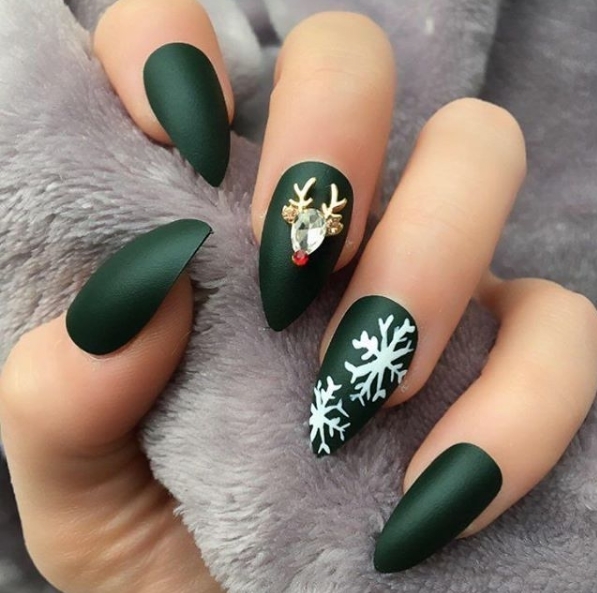 Оформление ногтей в темно-зеленом цвете с белыми снежинками и оленем из декоративных камней