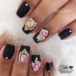 Черный дизайн ногтей с серебристыми стразами в лунках и цветами ручной лепки, украшениями-коронами