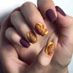 Фиолетовый матовый маникюр с желто-оранжевым оформлением трех ногтей и рисунками листьев