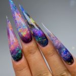Космические ногти-стилеты с преобладанием насыщенного синего оттенка и золотистыми блестками