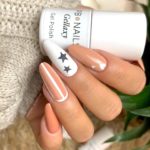 Бежево-персиковые ногти с вставками белого цвета, темными звездами и сердечками разного размера