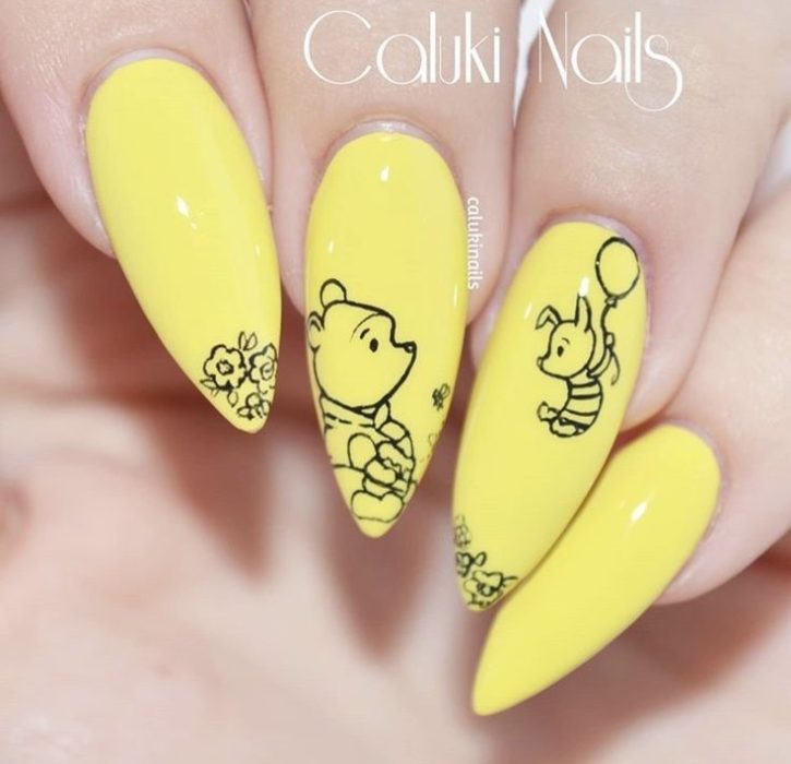 Желтый глянцевый маникюр на заостренные ногти с простыми черными рисунками Пятачка и Пуха