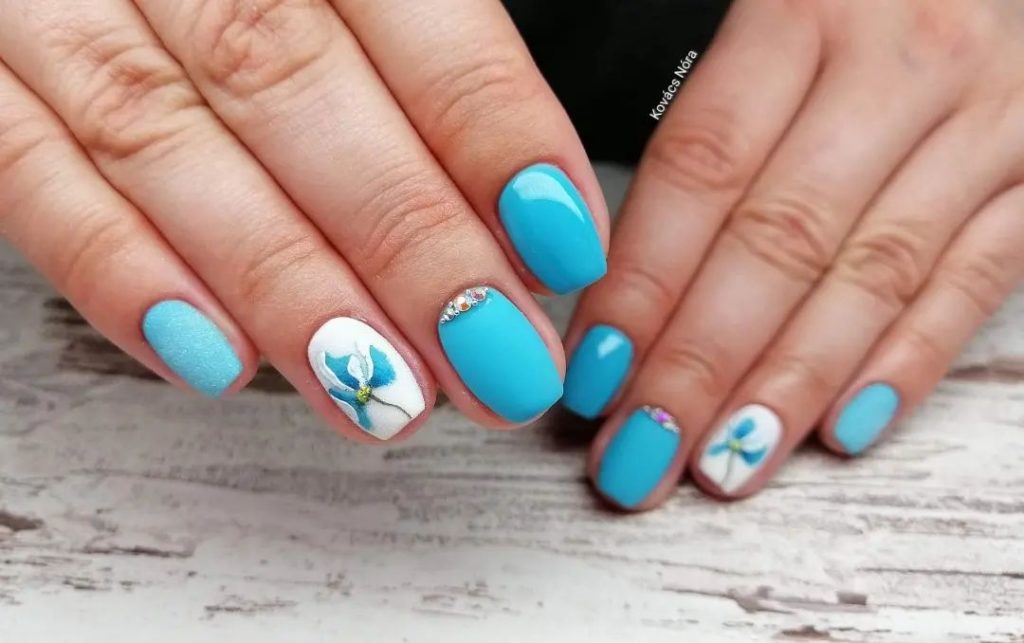 Бело-голубой дизайн ногтей с изящными рисунками цветов и мини-стразами в лунках