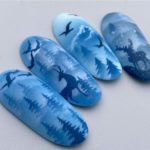 Дизайн ногтей в синем и голубом цвете с теневыми рисунками оленей, птиц, деревьев, гор