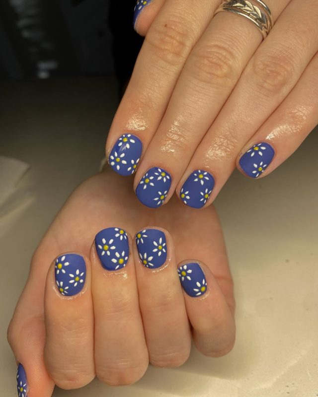 Аккуратный маникюр синего цвета на короткие ногти с рисунком цветов ромашек