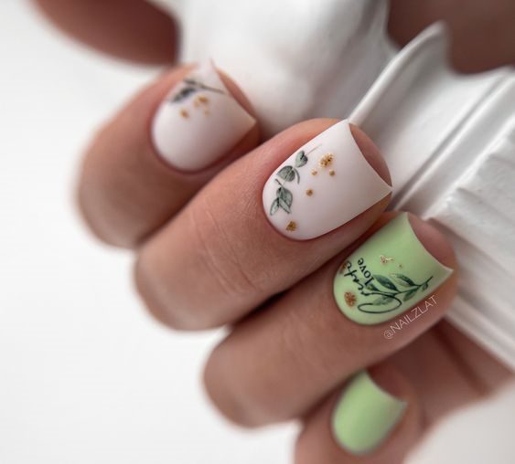 Квадратные короткие ногти в молочном и фисташковом цвете с маленькими рисунками листьев и вкраплением потали