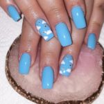 Насыщенно-голубой дизайн ногтей с дизайном в виде белоснежных облачков и с украшениями-стразами