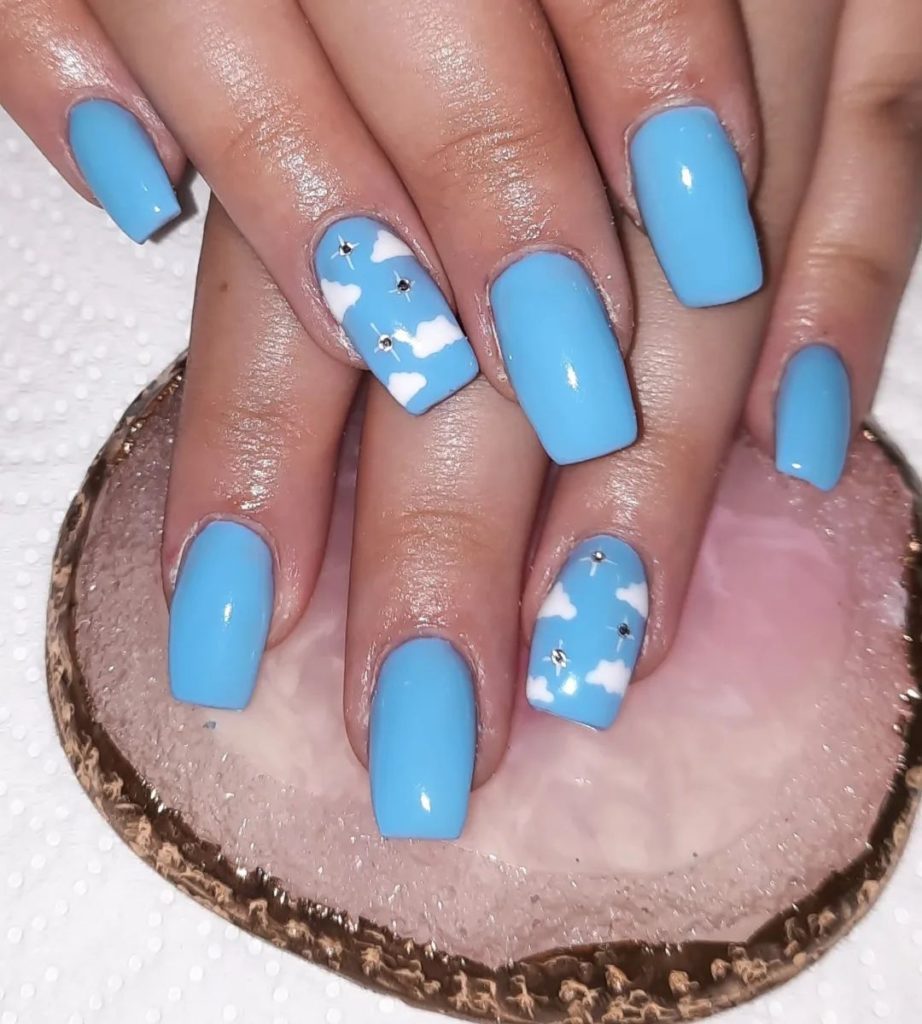 Насыщенно-голубой дизайн ногтей с дизайном в виде белоснежных облачков и с украшениями-стразами