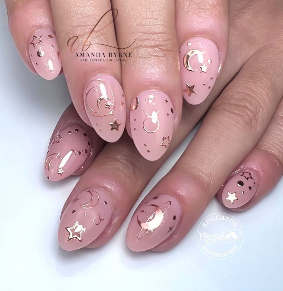 Нежно-розовый миндалевидный дизайн ногтей с золотистыми наклейками в виде луны, звезд