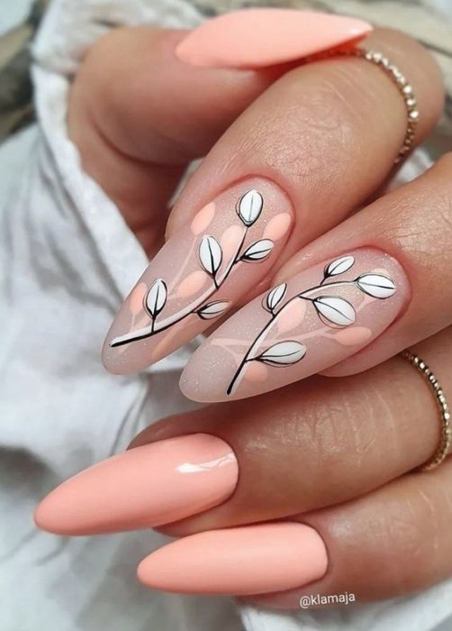 Нежный персиковый дизайн ногтей с рисунками листьев на ветках на двух ногтях