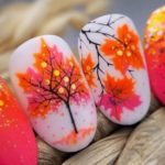Осенний дизайн ногтей с белым фоном, рисунками оранжево-розовых листьев, деревьев