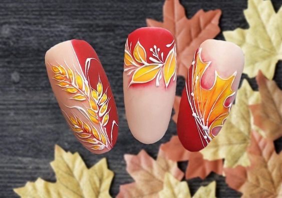 Осенний дизайн ногтей с желтыми рисунками листьев, колосьев на розово-красном фоне