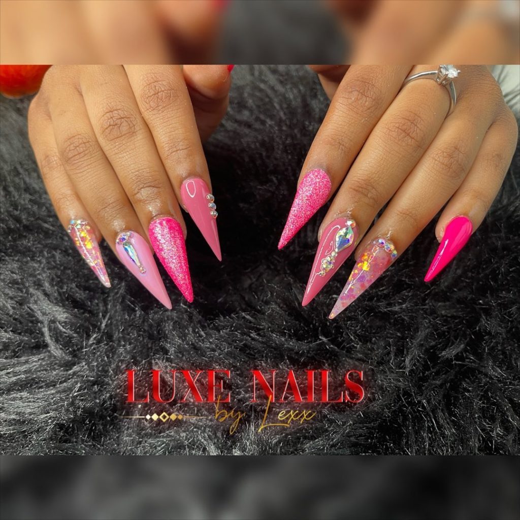 Розовые яркие ногти-стилеты с декором из стразов, камней разной формы, с блестками
