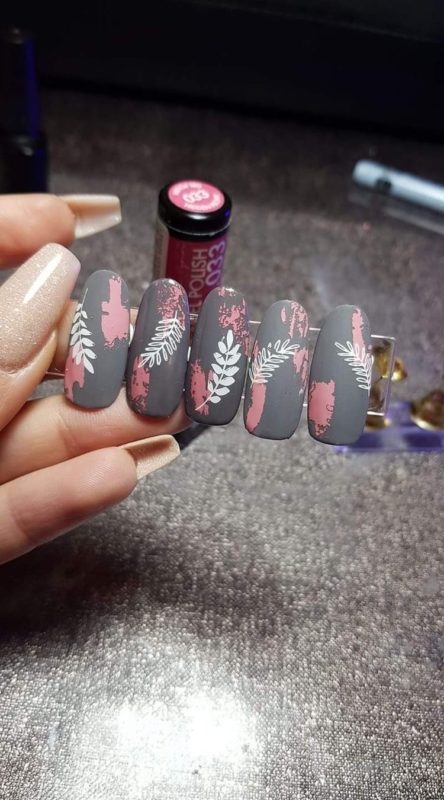 Серое матовое оформление ногтей с рисунками белых листьев, розовыми вставками