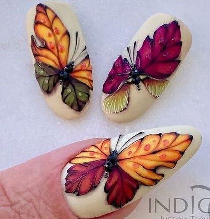 Светлый кремовый маникюр с рисунками в виде цветных бабочек с яркими крыльями