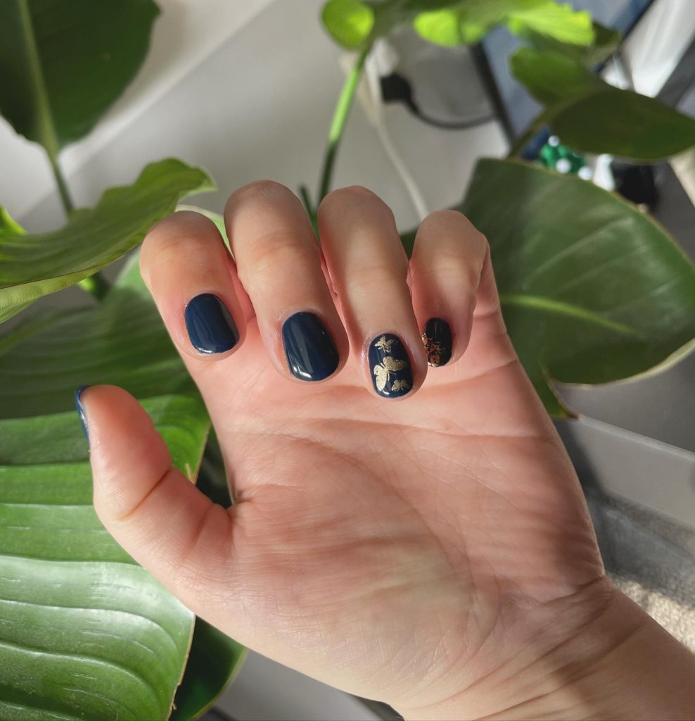 Темно-синее оформление коротких ногтей с золотистыми рисунками в виде бабочек разного размера