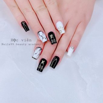Черно-белое оформление ногтей с надписями Louis Vuitton и брендовыми золотистыми значками
