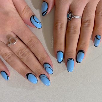 Черно-голубой дизайн ногтей миндалевидной формы с темными обрамлением на ярком фоне
