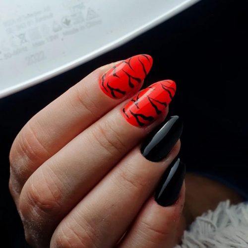 Черно-красный глянцевый маникюр на миндалевидные ногти с темными полосками тигра на ярком фоне