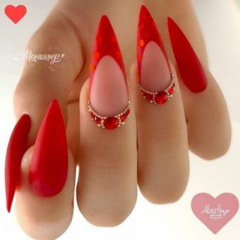 Французский маникюр в красном цвете на ногти-стилеты, украшенный декоративными камнями
