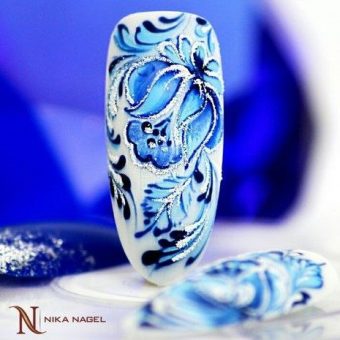 Изящный маникюр с белым фоном и сложными цветочными голубыми рисунками, блестками