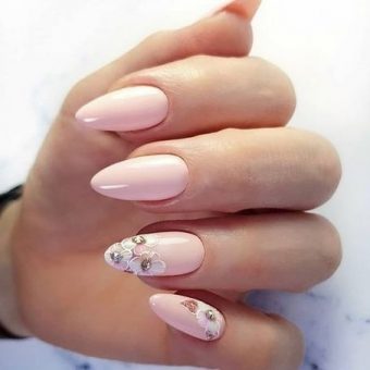 Лаконичный дизайн ногтей в нежно-розовом цвете с белоснежными цветами на двух пальцах