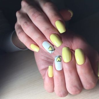 Летний теплый маникюр в лимонном цвете с изображением сердечек на безымянных пальцах
