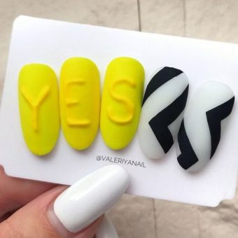 Оформление ногтей в желтом цвете с надписью «Yes» черно-белыми геометрическими узорами