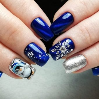 Синий новогодний маникюр с рисунком пингвина и использованием страз и блесток на ногти средней длины формы квадрат