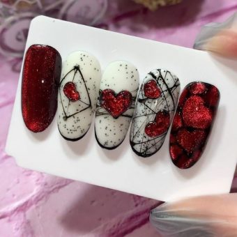 Современный дизайн ногтей в белом цвете с красным глиттером, рисунками сердец и черной паутинкой