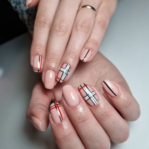 Светло-розовый дизайн ногтей с клетчатыми вставками на четырех пальцах