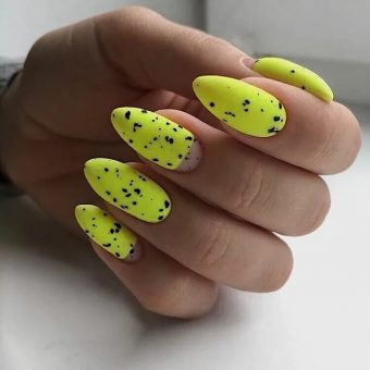 Желтый яркий маникюр на ногти миндальной формы с черными свободно разбросанными крапинками